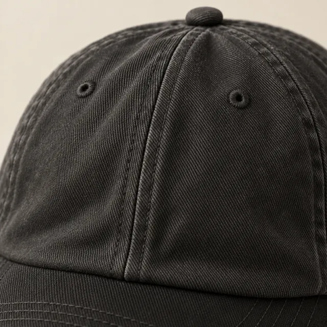 The soft front panels of a washed black twill cap, faded toward charcoal at the seams.