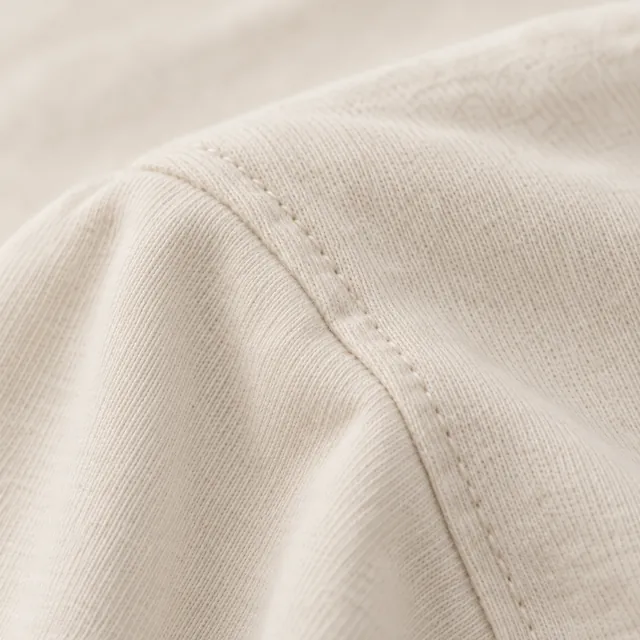 A stitched shoulder seam on smooth ecru jersey.