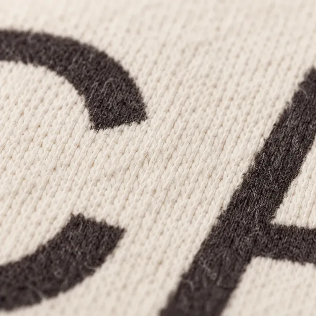 The thin strokes of small black printed capitals on ecru jersey, the knit showing through the ink.