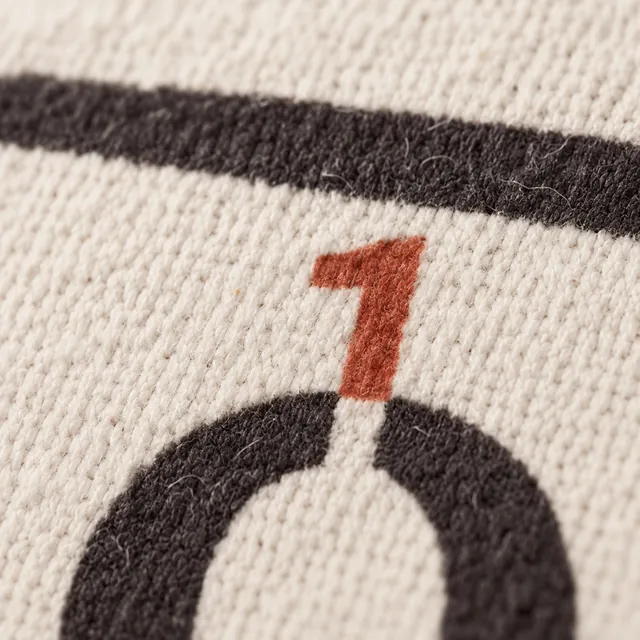 A black printed O on natural canvas, a small red 1 printed above it.