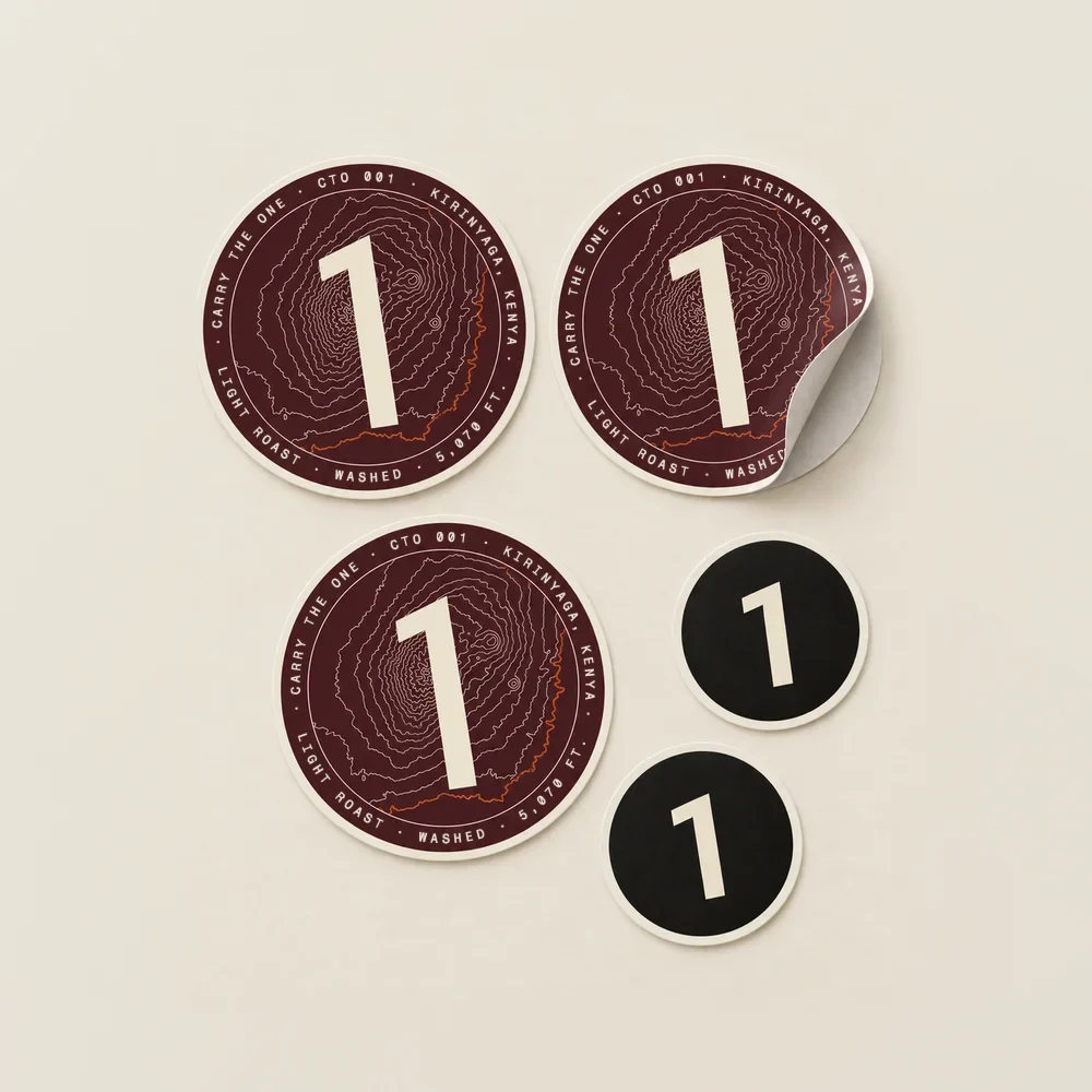 Die-cut vinyl stickers on paper: three plum CTO 001 discs with Mt. Kenya in cream contour lines, the 5,070 ft line in rust and the drop’s record round the rim, one peeling from its backing, and two smaller black discs with the 1.