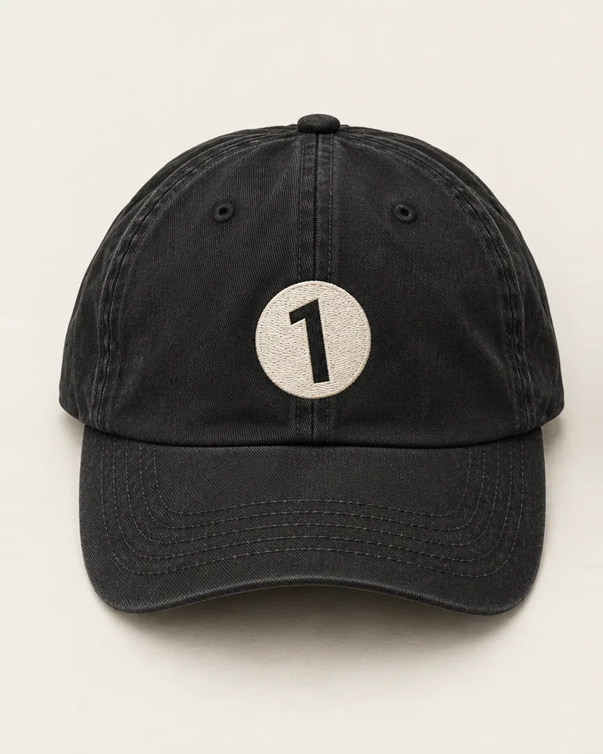 A washed black cap, a cream disc with the 1 stitched flat on the front.
