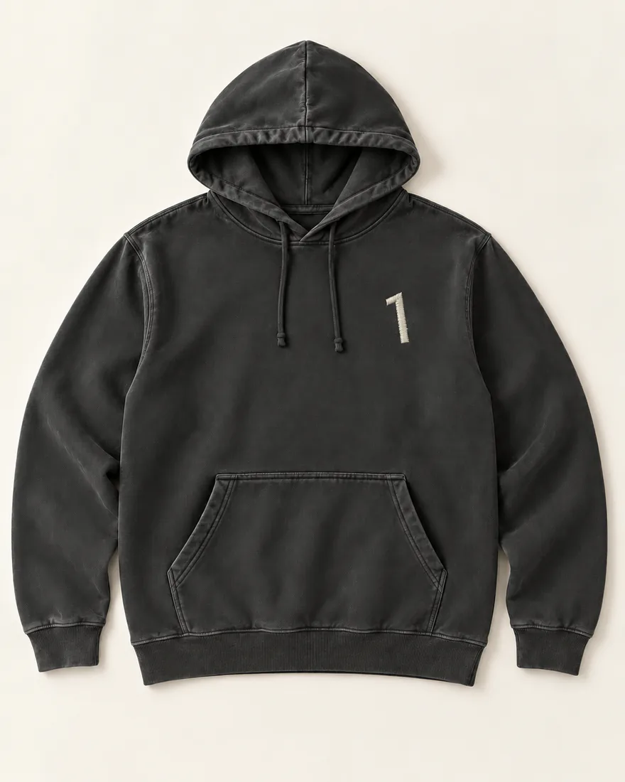 A washed black hoodie laid flat, the house’s 1 embroidered small in cream thread on the left chest.