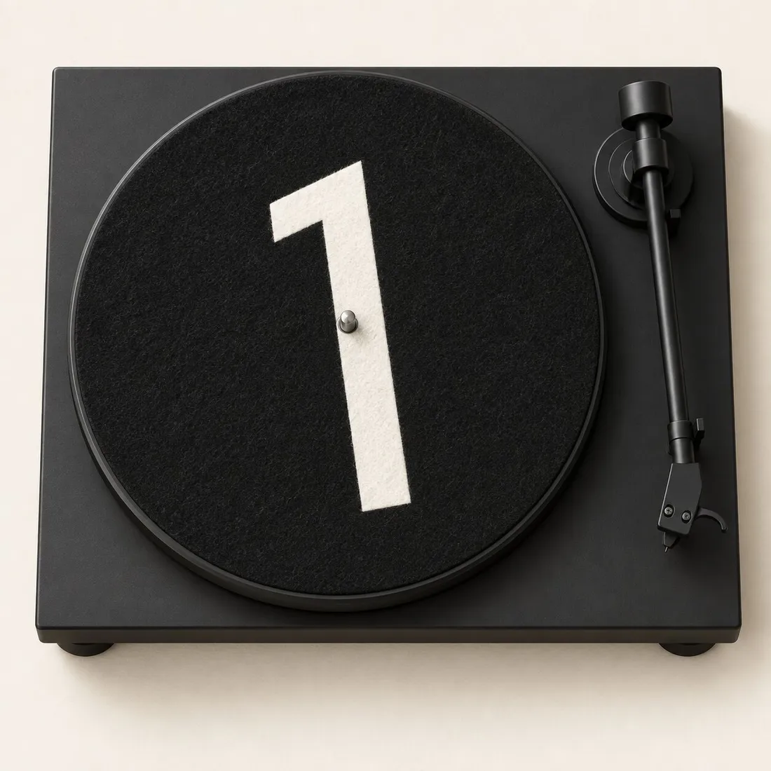 From above: a black felt slipmat with a large off-white leaning 1 on a matte black turntable, the tonearm at rest.