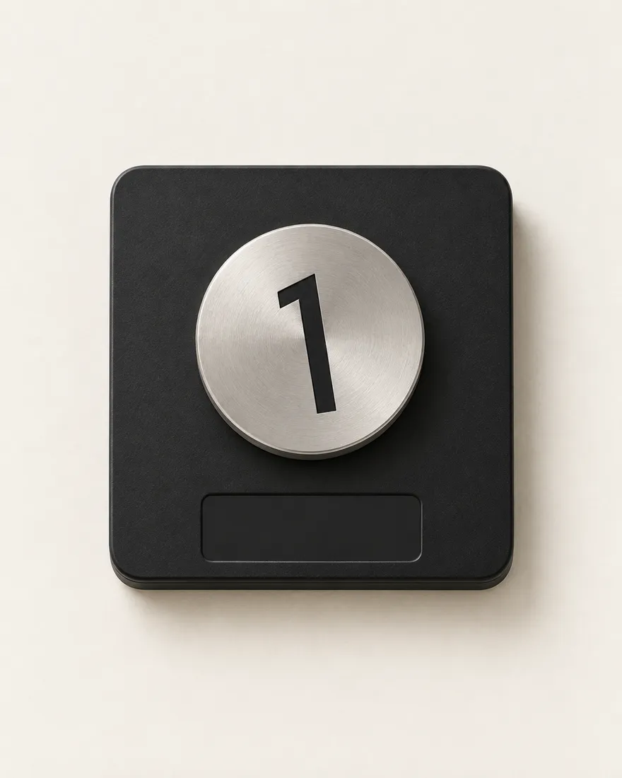 From above: a black pocket scale, a satin steel disc weight with the leaning 1 engraved in it on the platform, the display reading 100.0 g.